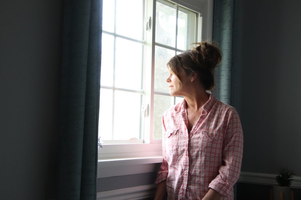 Woman looking out window somber look